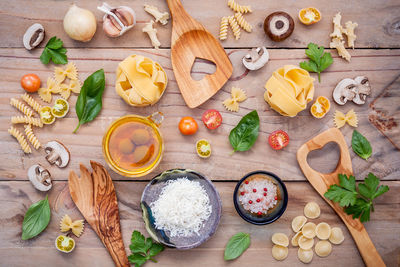 Directly above shot of raw pastas with ingredients on table