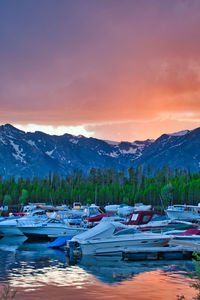 Boats moored at harbor against sky during sunset