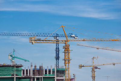 Cranes at construction site against sky