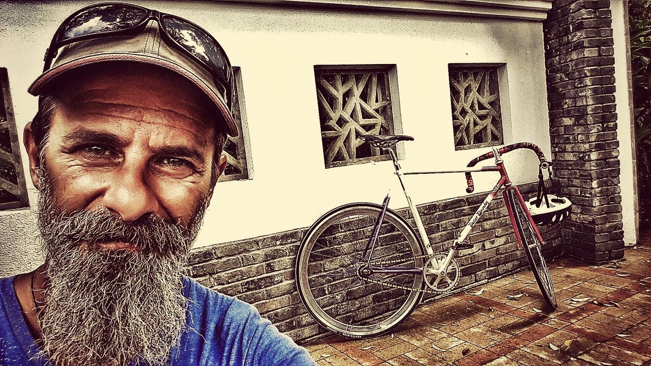 beard, portrait, one person, real people, looking at camera, front view, bicycle, lifestyles, headshot, day, building exterior, architecture, outdoors, young adult, close-up, people