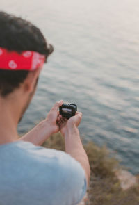 Side view of man holding action camera