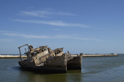 Abandoned ship in sea against sky