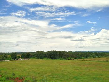 Scenic view of grassy field against cloudy sky