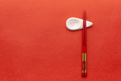 Directly above shot of chopsticks on red table