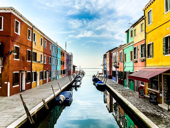 Canal amidst buildings in city against sky