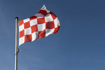 Low angle view of flag against blue sky