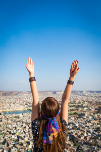 Woman with arms raised standing against townscape