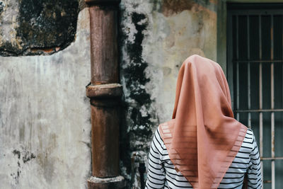 Rear view of woman standing by window of building