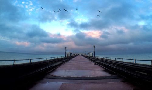 Pier on sea against cloudy sky