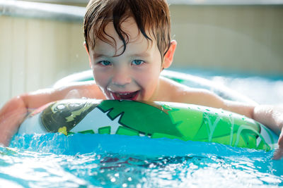 Portrait of happy boy swimming with inflatable ring in pool