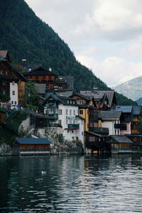 Houses by river against mountains and sky in city