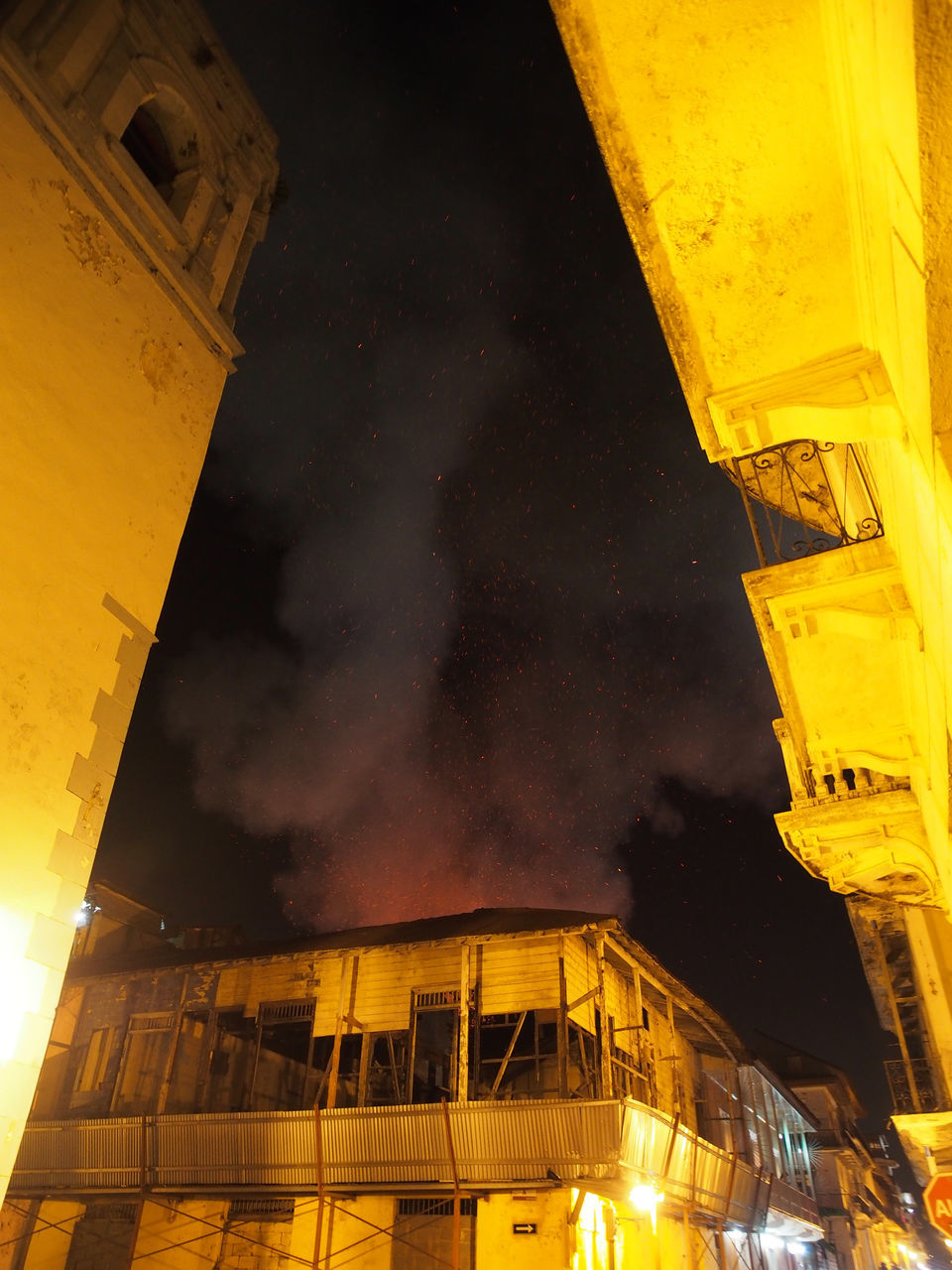 yellow, night, architecture, building exterior, built structure, light, low angle view, illuminated, building, city, nature, fire, no people, sky, outdoors, darkness, reflection