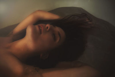 Close-up of shirtless woman lying down in bathtub