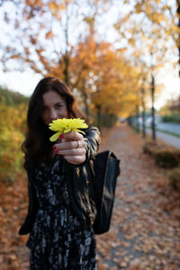 Young woman holding flowers in standing at park