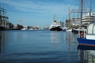 Sailboats moored on harbor in city against sky