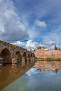 Arch bridge over river against sky