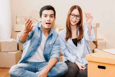 Portrait of young couple sitting with cardboard boxes at home