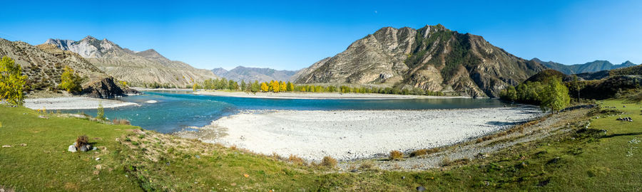 Panoramic view of lake and mountains against clear blue sky