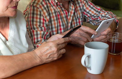 Midsection of man holding coffee cup on table
