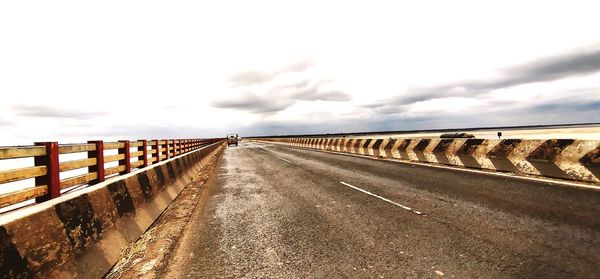 Road leading towards bridge against sky