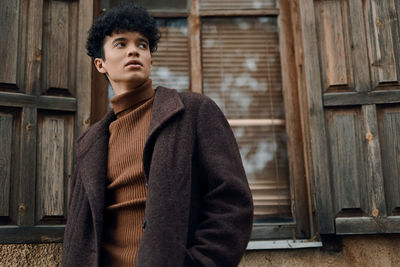 Portrait of young woman standing against wall