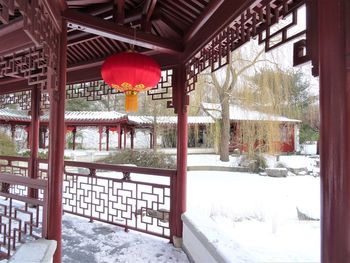 Lantern hanging on snow covered tree by building