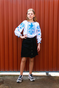 Ukraine child. ukrainian teen girl in vyshyvanka standing outside in skirt and sneakers. pray 