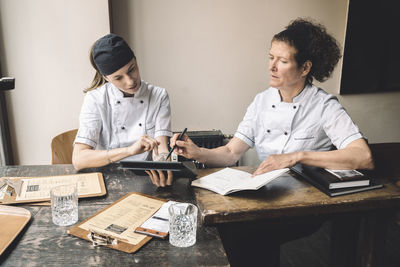 Female chefs discussing while sitting at table in restaurant