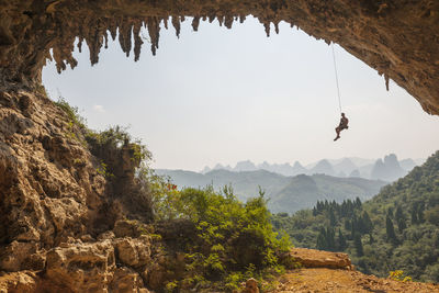 Man climbing the arch at odin's den next to moon hill in yangshuo