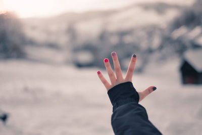 Kid showing hand with painted fingernails in front of a winter wonderland lanfscape
