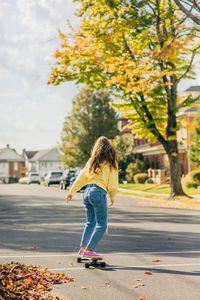 Full length of woman with umbrella on road during autumn