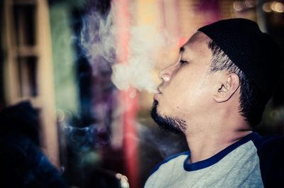 Close-up of young man with eyes closed smoking