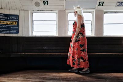 Rear view of woman standing by window