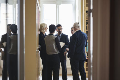 Lawyers discussing while standing in library seen from doorway