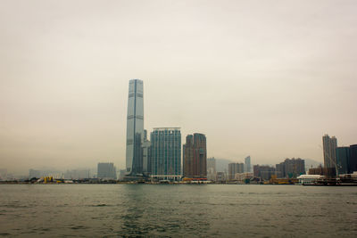 Sea by buildings in city against sky