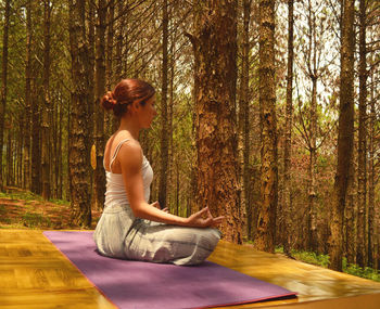 Side view of man sitting on table in forest