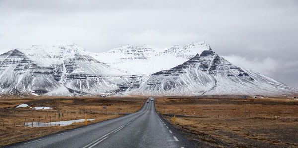 Road by snowcapped mountain against sky