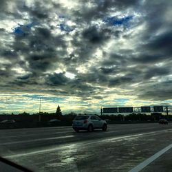 Cars on road against dramatic sky