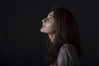 Portrait of young woman against black background