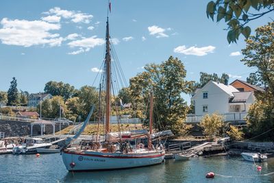 Boats moored in marina by buildings against sky