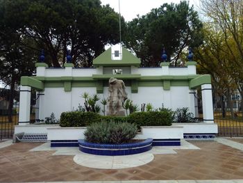 Statue by fountain against trees