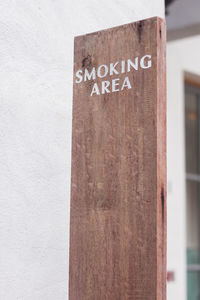 Close-up of text on wood against wall