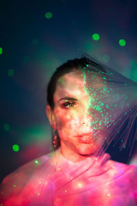 Close-up portrait of young woman against illuminated background