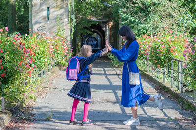 Schoolgirl daughter with backpack plays with her mother in park on way home from classes, girl wears