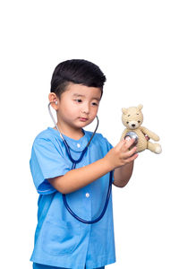 Cute boy holding toy while standing against white background