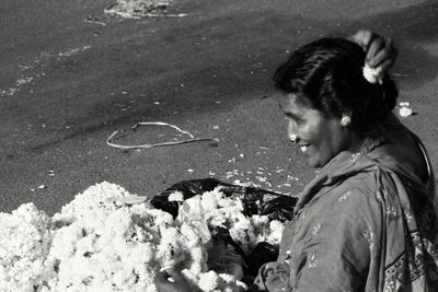 Side view of smiling woman selling flowers at market
