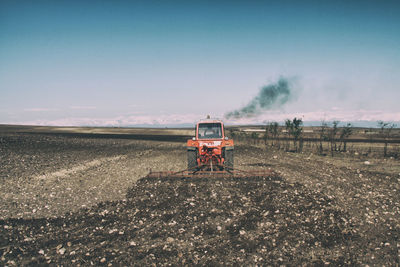 Tractor on agricultural field against sky