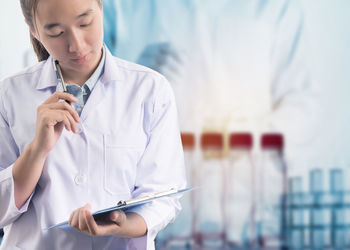 Close-up of doctor holding clipboard standing in laboratory