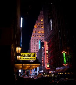 Illuminated street amidst buildings in city at night