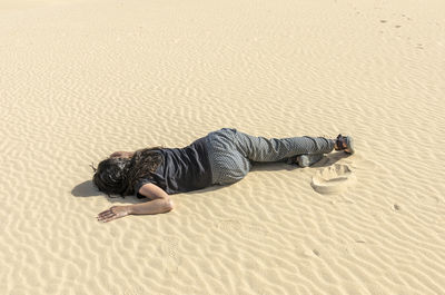 High angle view of woman lying on sand at beach